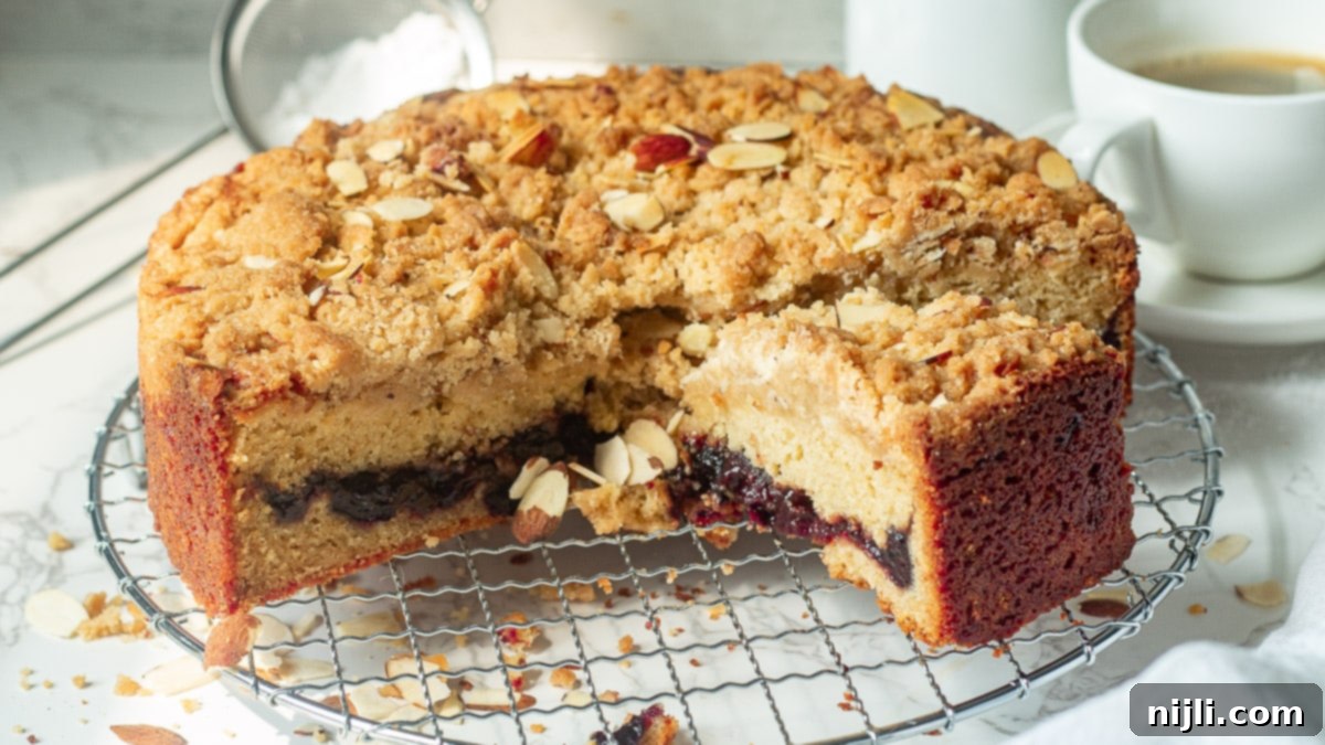 A freshly baked cherry coffee cake, generously topped with a golden streusel and a light dusting of powdered sugar, displayed on a wooden serving tray, ready to be enjoyed.