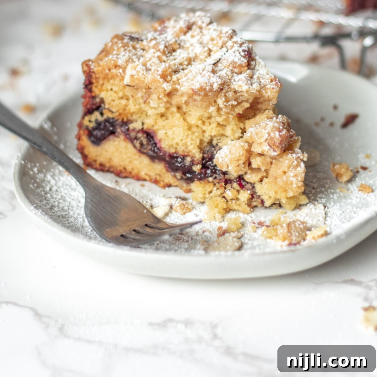 A beautiful top-down view of a freshly baked cherry coffee cake, showing the golden-brown crumb topping and the slight peek of cherry filling, indicating its rich layers and inviting texture.