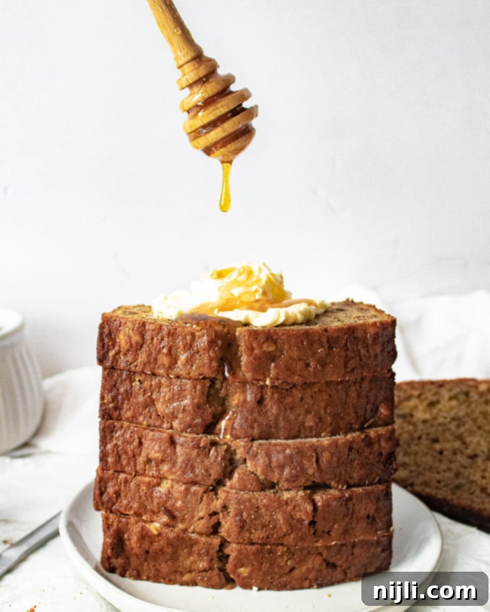 stacked pineapple banana bread with butter and a honey dripper drizzling honey on top