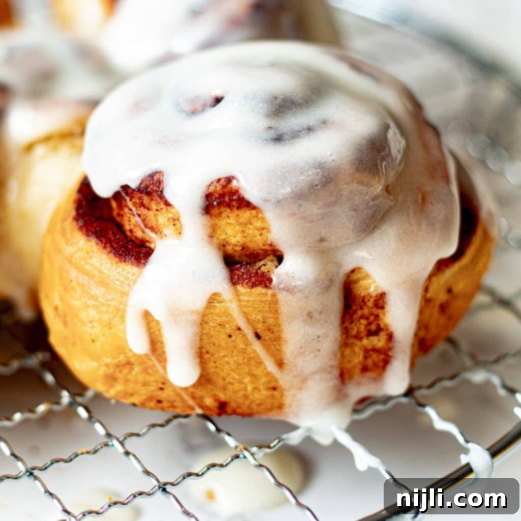 Air-Fried Cinnamon Rolls 2 close up of air fryer cinnamon rolls with icing on a cooling rack