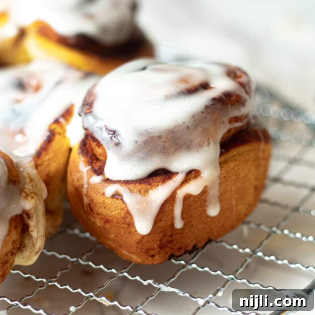 Air-Fried Cinnamon Rolls 5 air fryer cinnamon roll topped with icing on a wire rack, showing a perfect bake
