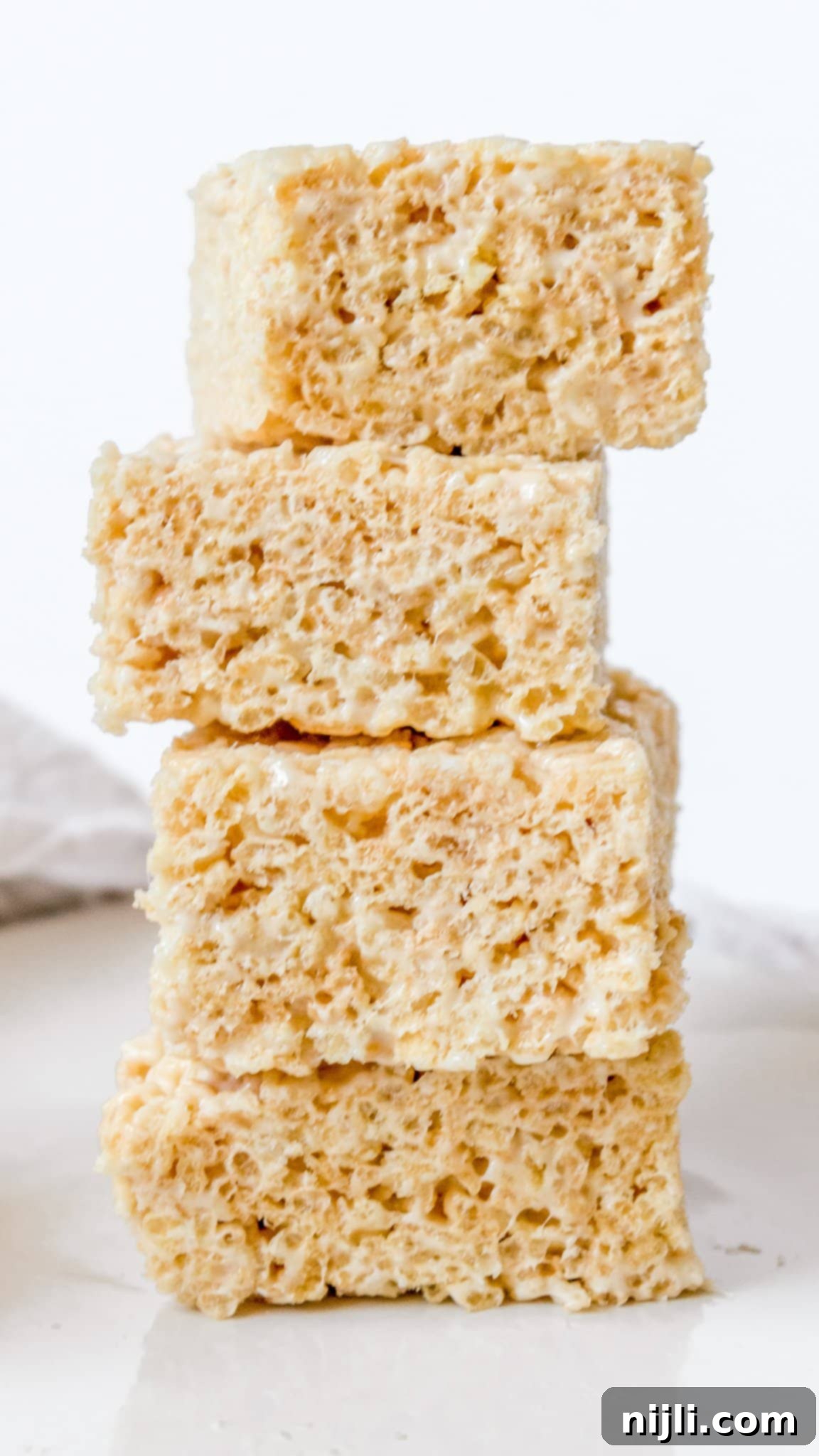 Gourmet Rice Krispie Treats with Brown Butter and White Chocolate Ganache 4 Elegant stack of vanilla-flavored fancy Rice Krispie treats, neatly cut into squares and displayed against a clean, white background, embodying simplicity and sophistication.