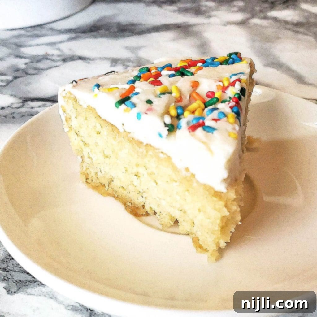 Easy Mini Vanilla Cakes Vanilla Buttercream 4 A perfectly sliced mini vanilla birthday cake on a plate, showing its moist interior and a thick layer of vanilla buttercream.