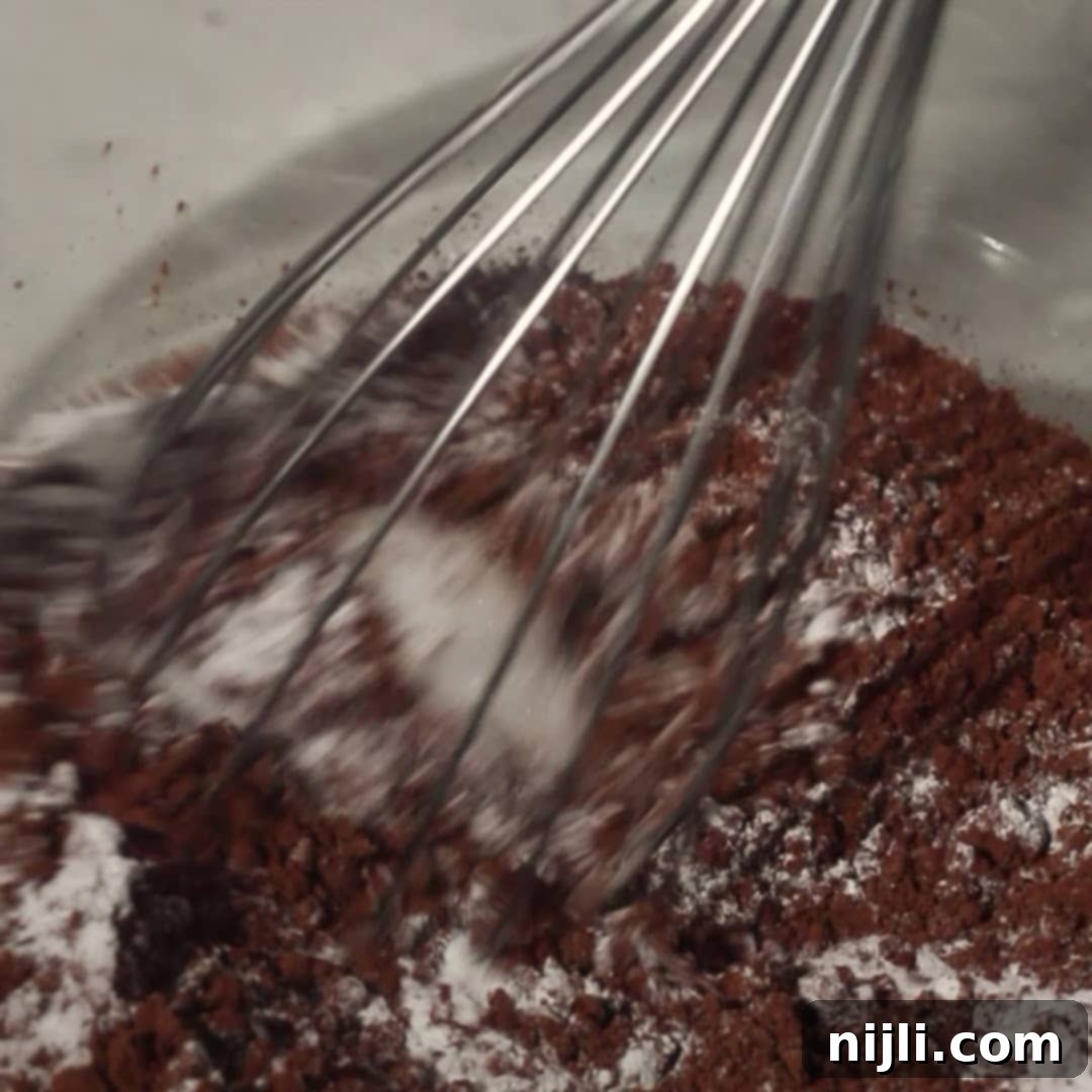 Mixing dry ingredients for the chocolate mousse cake batter in a glass bowl.