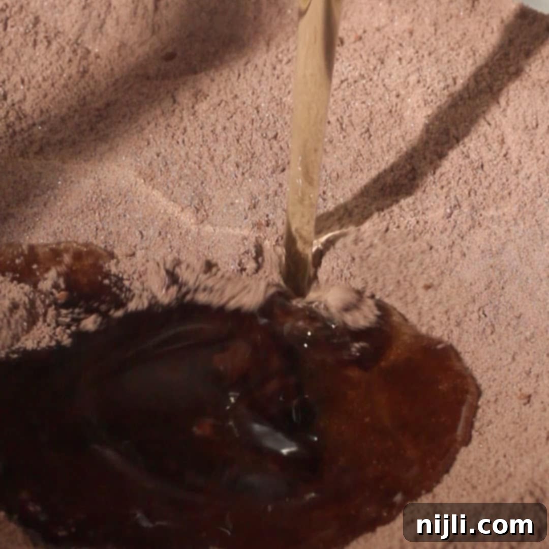 Pouring vegetable oil into dry ingredients for chocolate mousse cake.