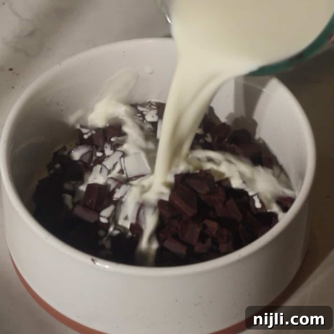 Pouring warm cream over chopped chocolate to create glossy chocolate ganache for the chocolate mousse cake.