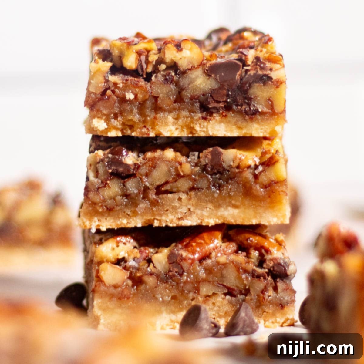 Chocolate pecan pie bars sliced on parchment paper with rich filling and a crisp shortbread crust.
