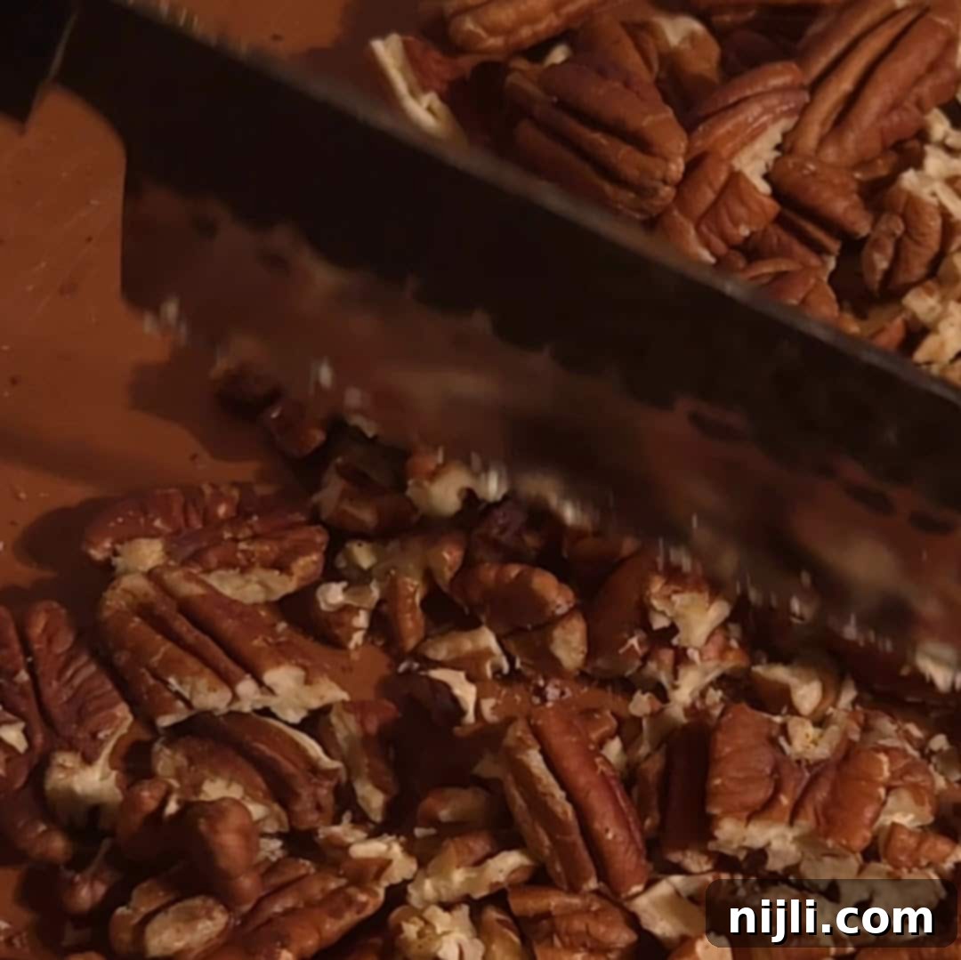 Chopping pecans on a wooden cutting board for the pecan pie filling.