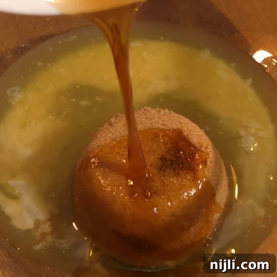 Pouring vanilla into the pecan filling mixture for chocolate pecan pie bars.