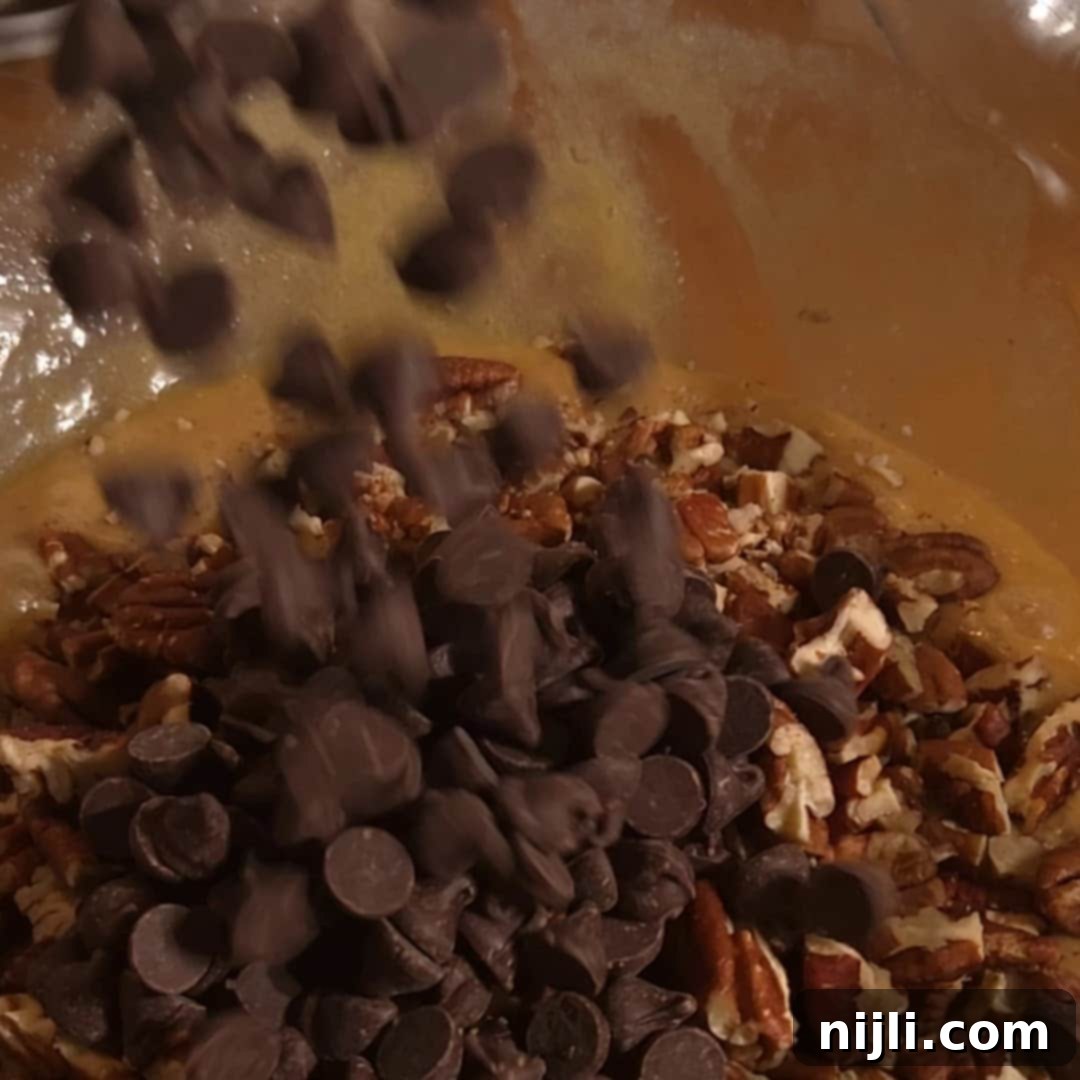 Adding chocolate chips to the pecan pie filling mixture for gooey chocolate pecan bars.