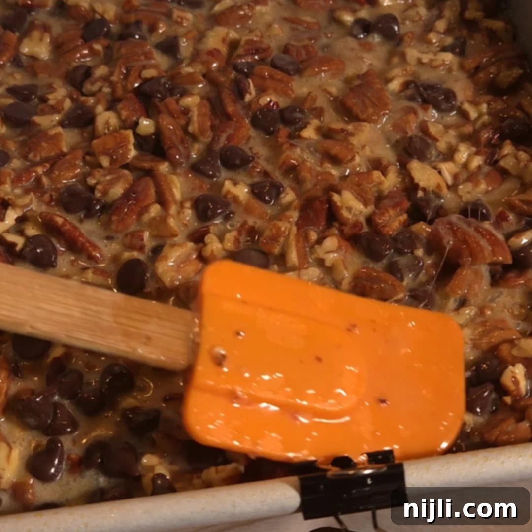 Spreading chocolate pecan filling evenly in a baking pan before baking.
