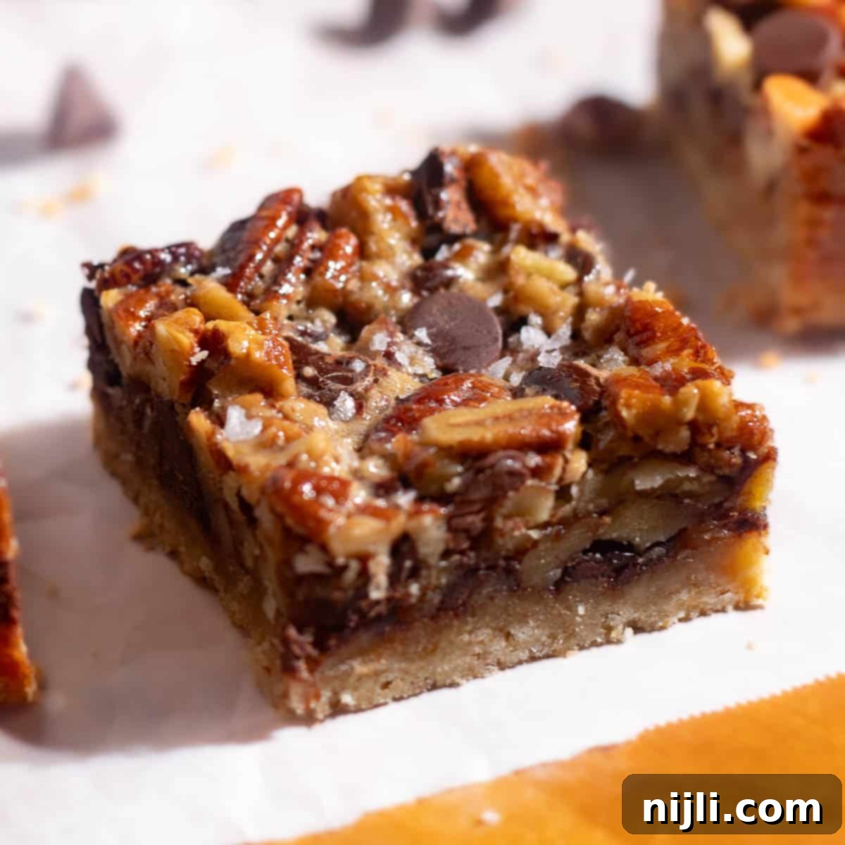 Close-up of pecan chocolate bars showing caramelized pecans and chocolate chunks baked into a golden crust.