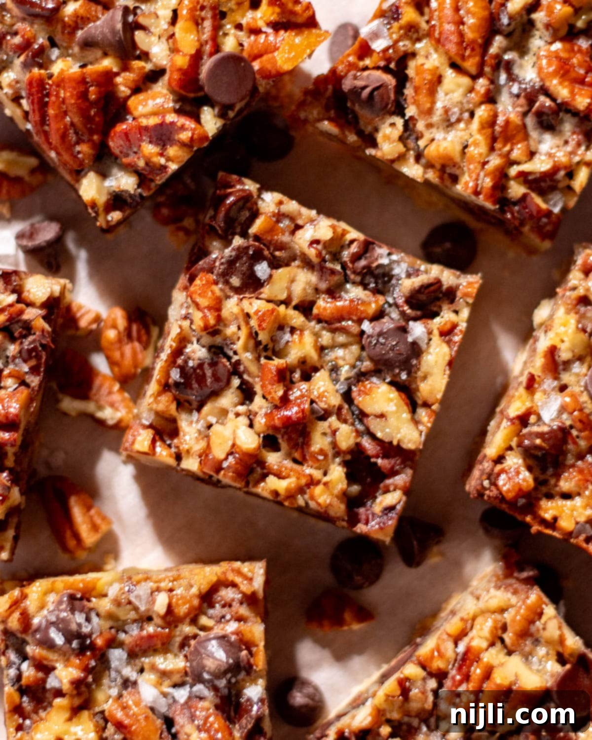 Overhead shot of chocolate and pecan dessert bars with chunks of pecans and melted chocolate chips.