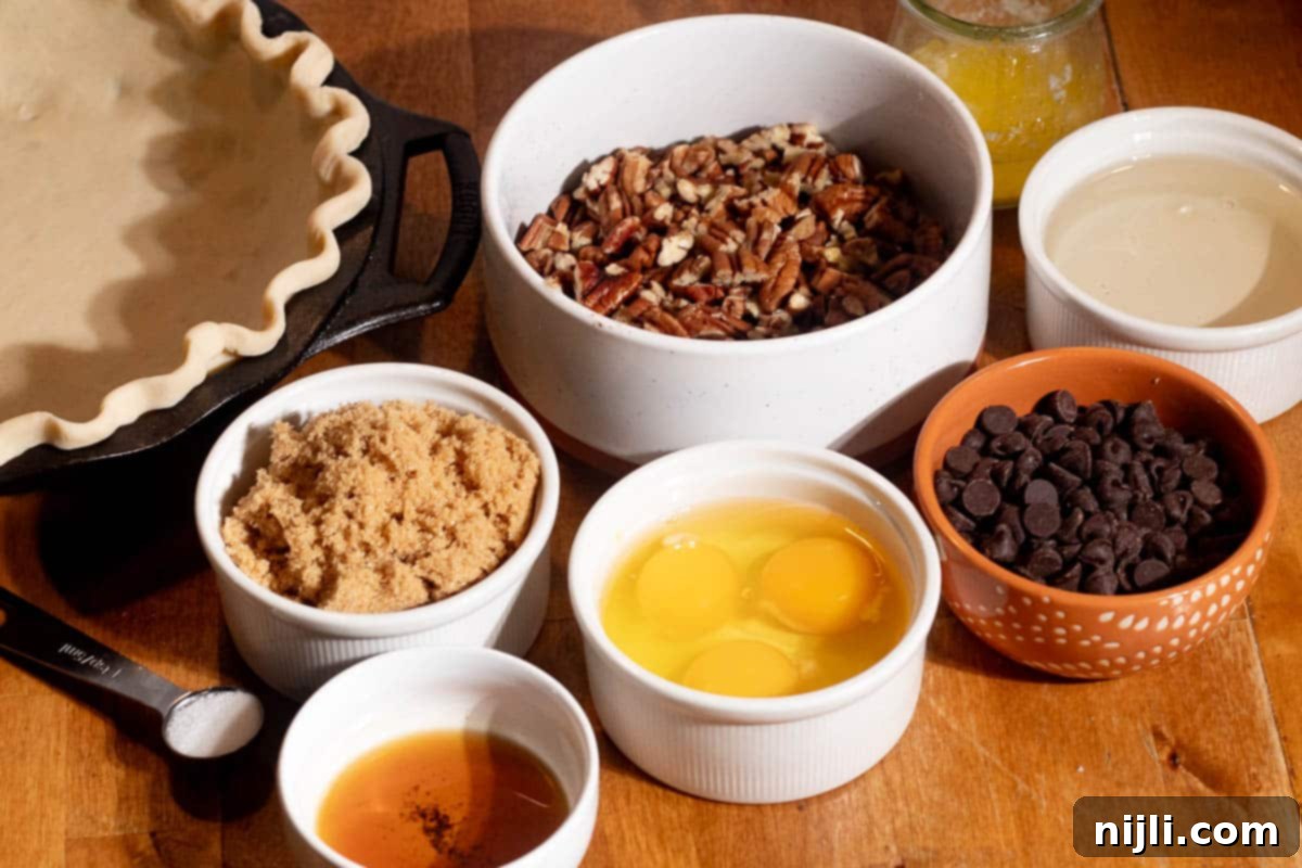 Ingredients for chocolate chip pecan pie including pecans, chocolate chips, eggs, brown sugar, butter, and pie crust.