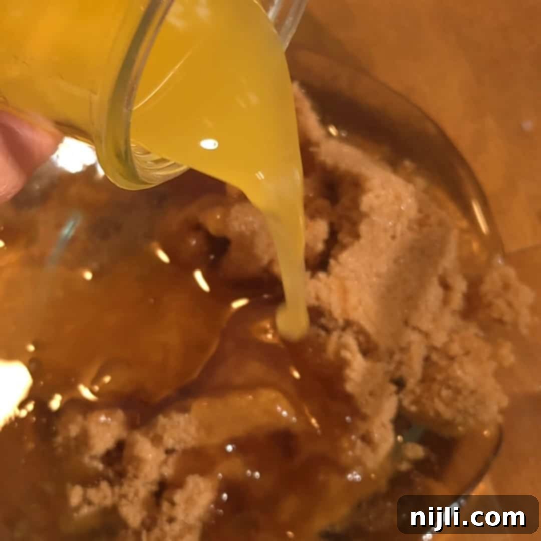 Pouring melted butter over brown sugar to make the rich filling for chocolate chip pecan pie.