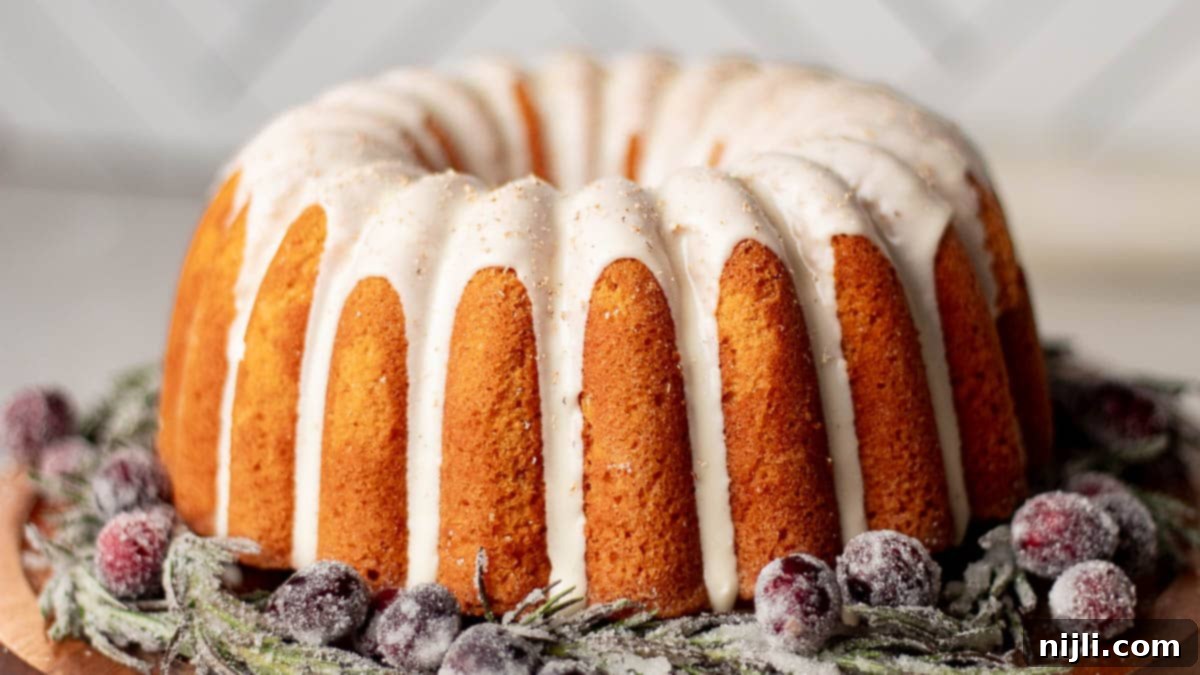 Classic old-fashioned eggnog bundt cake drizzled with thick glaze and surrounded by sugared rosemary and cranberries.