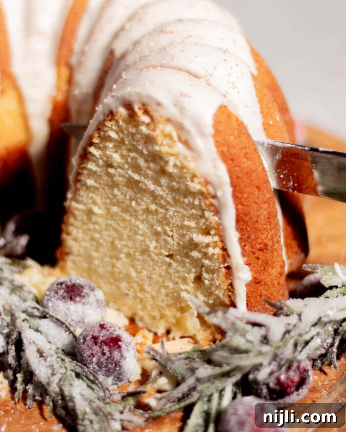 Sliced eggnog pound cake showing soft, buttery texture topped with smooth eggnog glaze and dusted with nutmeg.