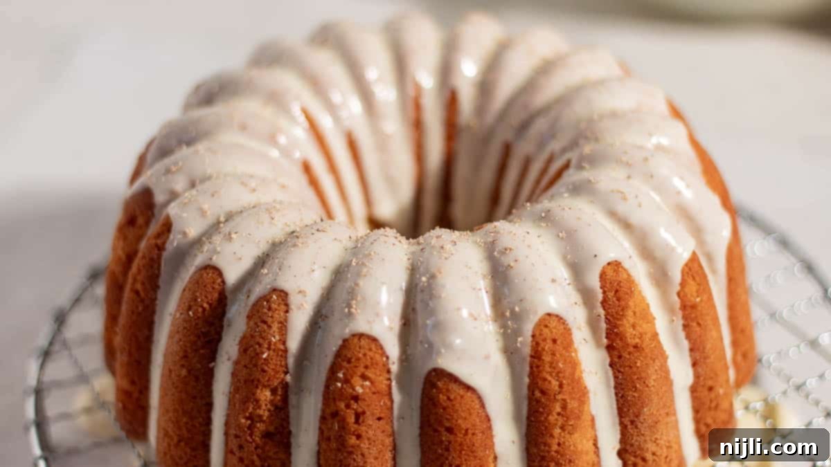 Golden eggnog bundt cake cooling on a wire rack with creamy glaze drizzled on top, perfect for holiday baking.