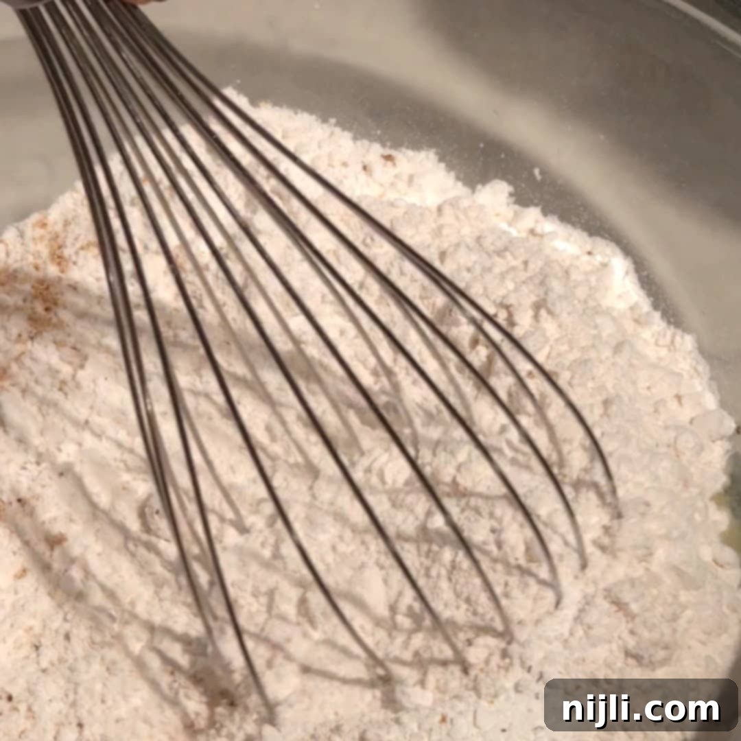 Whisking cake flour, baking powder, and freshly grated nutmeg in a separate bowl.