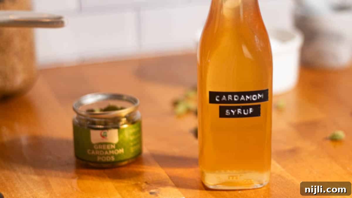 Bottle of cardamom syrup beside green cardamom pods in a jar, perfect for homemade coffee or cocktail recipes.